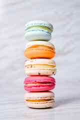 Macaron pink, orange and beige, blue on marble style. French dessert on top of each other, appetizing, diet