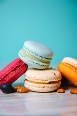Colorful macarons. Small French cakes. Sweet and colorful french macaroons. Many tasty macarons with fresh berries, raspberries and blueberries, nuts and strawberries on a green background