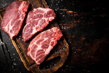 Raw pork steak on a wooden cutting board. 