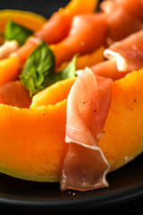 melon with parma on a dark background