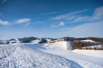 a snowy landscape featuring hills in the background with a blue sky