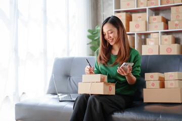 Portrait of Starting small businesses SME owners female entrepreneurs working on receipt box and check online orders to prepare to pack the boxes, sell to customers, SME business ideas online.