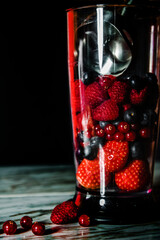 Fruit in a blender, mixer. Fruit cocktail and healthy food and drinks. Strawberry, raspberry, blueberry. Diet and vitamins for health, nutrition smoothie diet on a black background.