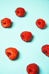 Raspberry pattern on the blue color of the lagoon. Fruits and healthy food, trendy photo.