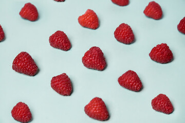 Raspberry pattern on the blue color of the lagoon. Fruits and healthy food, trendy photo.