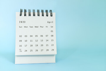 Selective focus of April 2023 desk calendar on blue background with copy space.