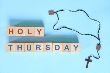 Maundy Thursday holy week concept. Wooden blocks typography with rosary flat lay in blue background.