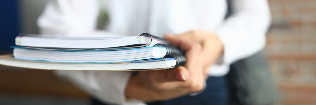 Female student holds folder and notebook in hands for studying