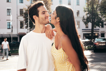 Naklejka premium Smiling beautiful woman and her handsome boyfriend. Happy cheerful family. Sexy couple posing in the street at sunrise. During romantic date at sunny summer day outdoors. Looking at each other