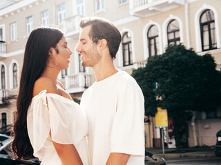 Smiling beautiful woman and her handsome boyfriend. Happy cheerful family. Sexy couple posing in the street at sunrise. During romantic date at sunny summer day outdoors. Looking at each other