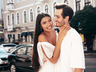 Fototapeta premium Smiling beautiful woman and her handsome boyfriend. Happy cheerful family. Sexy couple posing in the street at sunrise. During romantic date at sunny summer day outdoors. Looking at each other