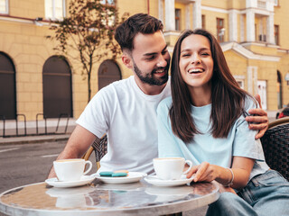 Smiling beautiful woman and her handsome boyfriend. Happy cheerful family. Couple drinking coffee in restaurant. They drinking tea at cafe in street. Holding cup. Enjoying their date