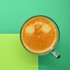 glass of hot black coffee put on green background