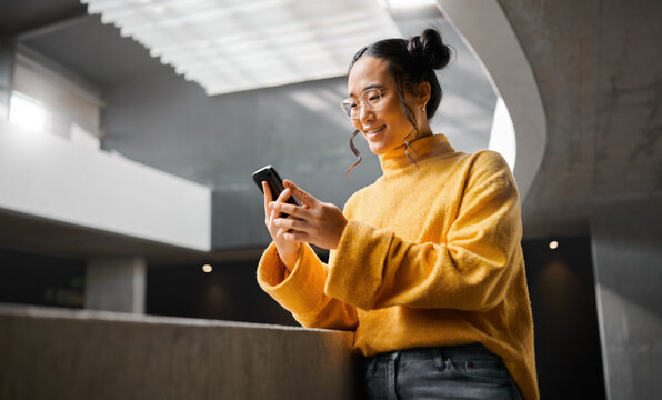 Phone, texting and woman in office building, happy and smile while on internet, search and reading. Asian, girl and business entrepreneur on smartphone for research, social media or browsing in Japan