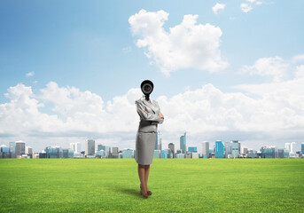 Camera headed woman standing on green grass against modern cityscape