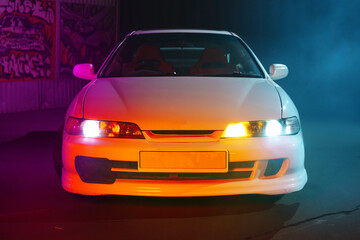 Fototapeta na wymiar 90s sport car with smoke in neon light on the asphalt road at night