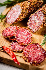Cut into pieces of salami on a wooden cutting board. 