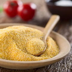 Raw coarsely ground cornmeal or polenta on wooden plate with wooden spoon (Selective Focus, Focus...