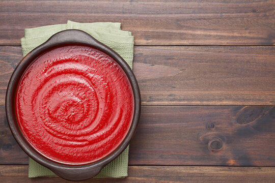 Tomato paste in rustic bowl, photographed overhead on wood with copy space on the side (Selective Focus, Focus on the tomato paste)