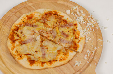 Closeup top view studio shot of tasty delicious Italian homemade mozzarella cheesy ham pineapple original Hawaiian pizza soft bread crust on wodden plate served on table in restaurant.