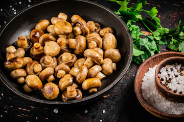 Frying pan with fried small mushrooms with parsley. 