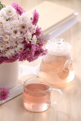 Fototapeta na wymiar Fresh delicious herbal tea, books and beautiful bouquet on wooden table