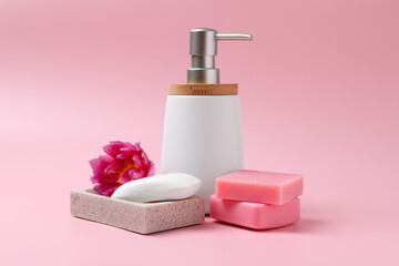 Obraz na płótnie Canvas Soap bar and bottle dispenser on pink background