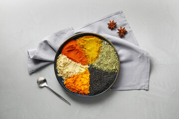 Plate with different spices on light grey table, flat lay
