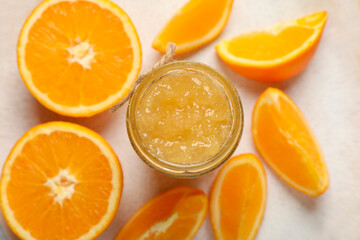 Jar of delicious orange jam and fresh fruits on plate, flat lay