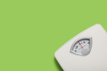 Bathroom scale on light green background, top view. Space for text