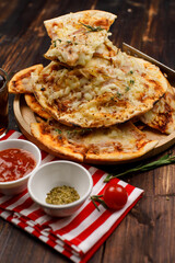 Closeup shot multiple stack hot oven baked tasty delicious Italian homemade ham pineapple traditional Hawaiian bread crust pizzas on wood plate serving with tomato ketchup and herbs with soft drink