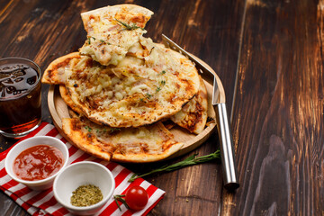 Closeup shot multiple stack hot oven baked tasty delicious Italian homemade ham pineapple traditional Hawaiian bread crust pizzas on wood plate serving with tomato ketchup and herbs with soft drink