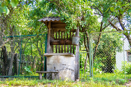 Old well with iron bucket on long forged chain for clean drinking water