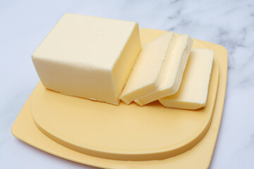 Freshly cut butter on a yellow plate. Butter pieces.