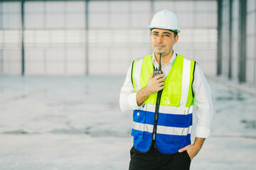 warehouse manager with tablet and radio communication his worker working in background in warehouse...