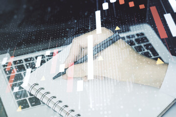 Abstract creative financial graph with world map and with hand writing in diary on background with laptop, financial and trading concept. Multiexposure