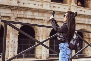 Rome Italy,  travel tourism travel concept. Young  beautiful woman taking a pictures of Colosseum   and tourist crowds.