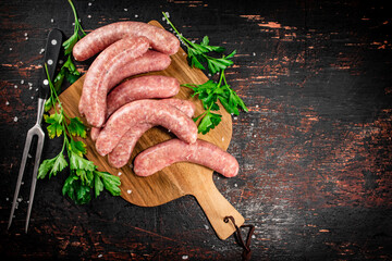 Raw sausages on a cutting board with parsley.  - 564171657