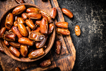 Dates in a plate on a cutting board. 