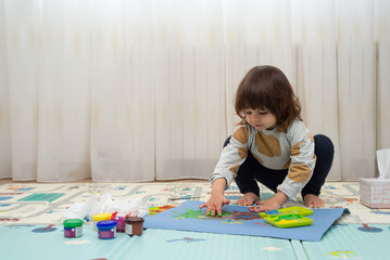 Female toddler finger painting in a playroom.