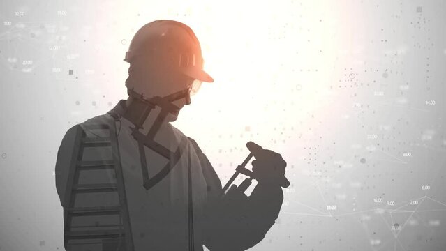 Footage computer graphics and double exposure. The silhouette of a man in a protective helmet and with equipment is flooded with a video from an oil rig against a background with digital graphs.