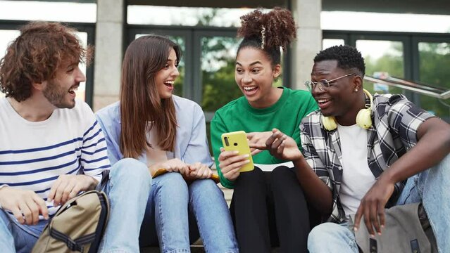 Group of university student friends sitting together using mobile phones to share content on social media