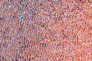 Abstract rhinestones background. Texture of rhinestones illuminated with multi-colored light. Pink...
