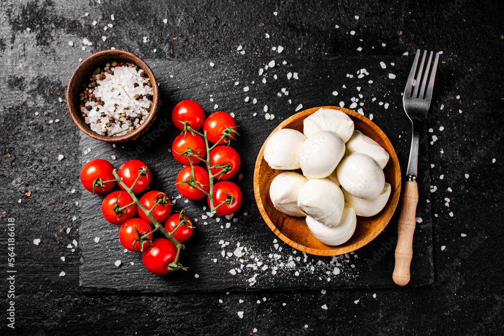 Poster Mozzarella cheese in a plate on a stone board with tomatoes and spices.