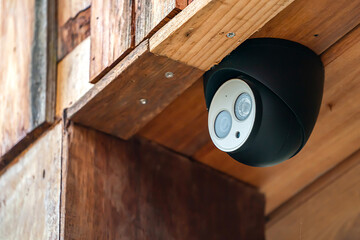 close up mini CCTV camera black case is set up on the wood ceiling building.