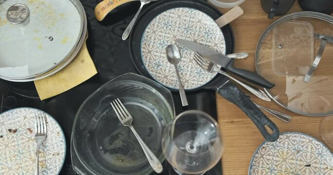 Top view, dirty dishes, plates in kitchen. Bowl, dishware, glass in leftover food. Kitchenware mess at home. Messy, unhygienic, unwashed in kitchen. Close up panning of many neglected dirty utensils