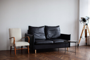 Retro interior with black sofa. White chair and wooden floor.
