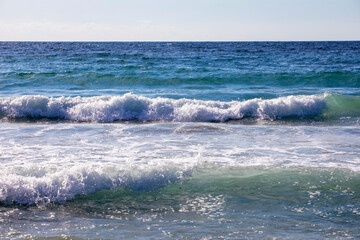 Aegean Sea by day in storm, resort, foam, against sun