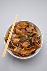 Fried noodles with vegetables and beef in white dish