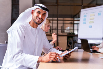 Handsome arab businessman wearing emirates kandora working at his desk in the office, Dubai